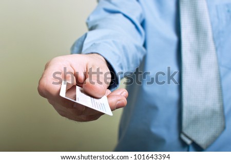 Businessman presenting credit card with shallow depth of field, focus on the card. Shopping and spending concept