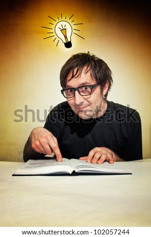 Man in black shirt reading a book with idea bulb above his head