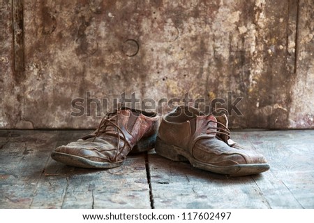 Old dirty brown leather shoes on wooden floor.