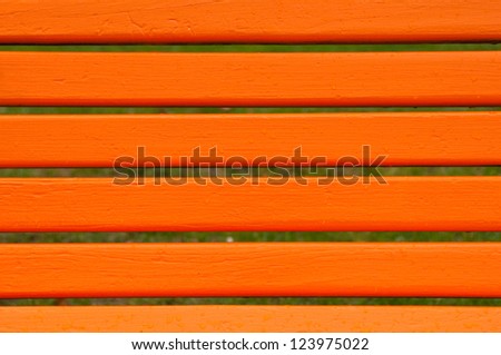 Orange park bench detail, close up image of wooden bars.