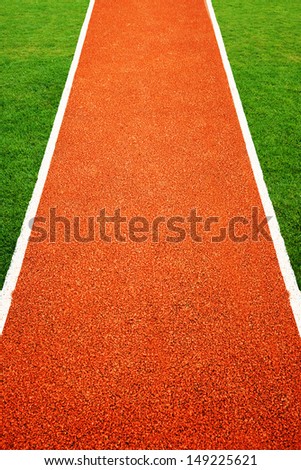 Orange athletics all weather running track texture in green grass.