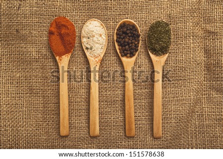 Spices, Food ingredients on wood spoons with open book on kitchen table, top view