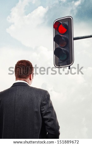 Businessman in front of red traffic light. Business obstacles concept.