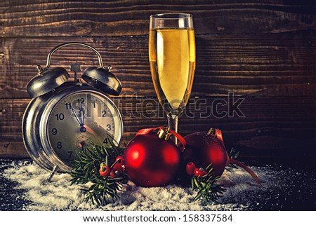 Christmas balls, a glass of champagne and vintage clock at five minutes to midnight on New Years Eve.