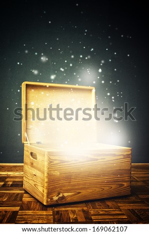 Open magical Wooden crate box on the floor with shiny particles flying around