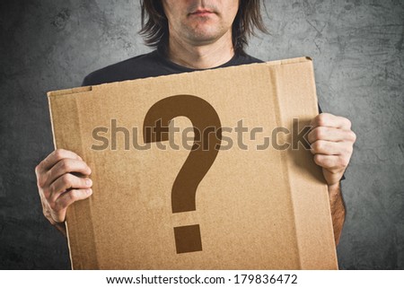 Man holding cardboard poster with question mark printed on.