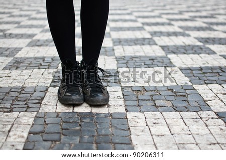 Woman in sneakers on the streets of Prague, on checkered pavement. Youth guidance, student guide, choose path concept, strategic planning.