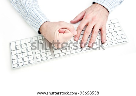 Angry businessman smashing computer keyboard on white desk top.