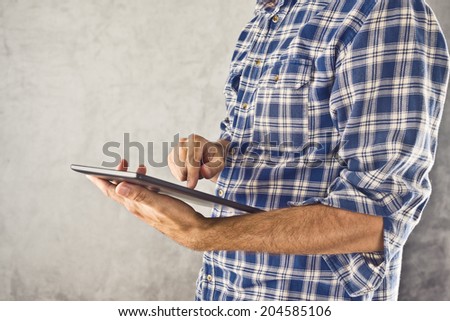 Casual man holding 10 inch display digital tablet computer and using it for internet browsing, e-book reading and other multimedial experience.
