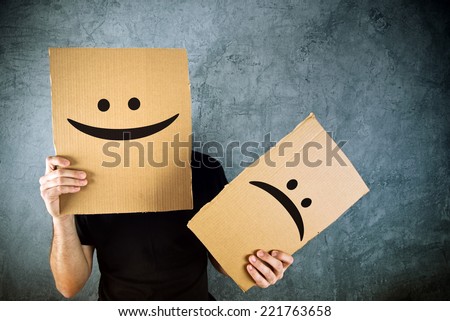 Putting a smiling face on. Man holding cardboard paper with smiley face printed on as happiness and joy concept.