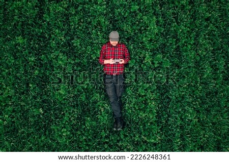 Drone operator, top view of man lying in grass field and using drone remote controller, copy space included Foto stock © 