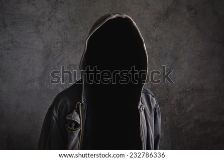 Faceless unknown and unrecognizable man without identity wearing hood in dark room, spooky criminal person.