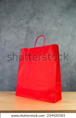 Red Paper Shopping Bag on Wooden Retail Store Table.