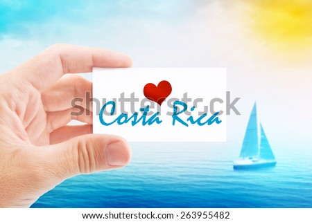 Summer Vacation on Costa Rica Beach, Person Holding Visiting Card for Summertime Holiday Message Love Costa Rica and Sailboat at Sea in Background.
