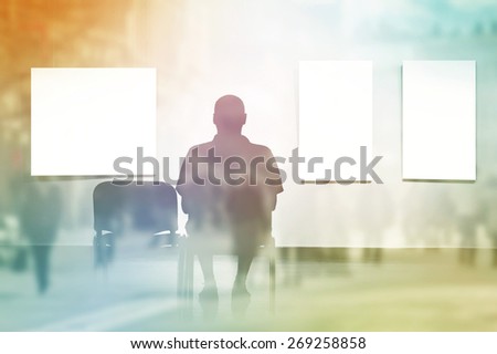 Double Exposure Silhouette of Man sitting in art gallery, looking at art displayed on walls.