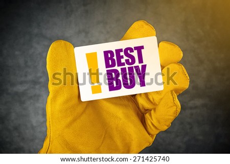 Male Hand in Yellow Leather Construction Working Protective Gloves Holding Best Buy Card as Shopping Recommendation Concept.