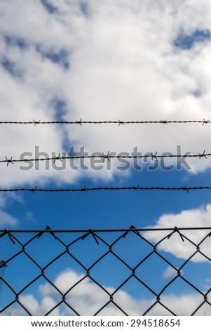 Barb Wire Fence, White Clouds and Blue Sky in Background, Dreaming of Freedom Concept