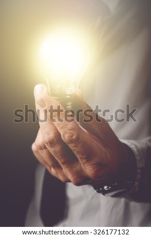 Bringing up the new ideas to company, businessman with light bulb offering new solutions to understanding problems in business, retro toned image, selective focus.