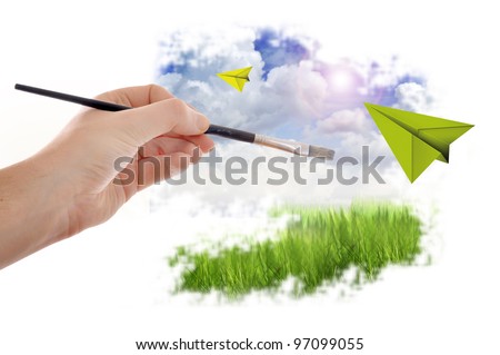 MAle hand with paint brush painting a beautiful summer landscape with blue sky and clouds