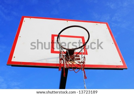 Basketball hoop with damaged net over blue sky.