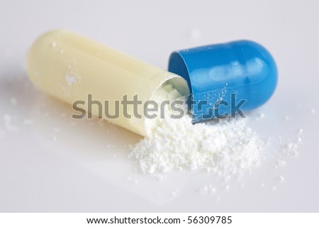 Close up of pill peeled into half with powder isolated on white background