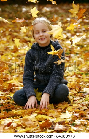 Little girl with autumn leaves falling around her