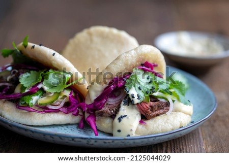 Steamed bao buns with beef steaak, pickled cucumber, erd cabbage and mustard mayo Stock fotó © 