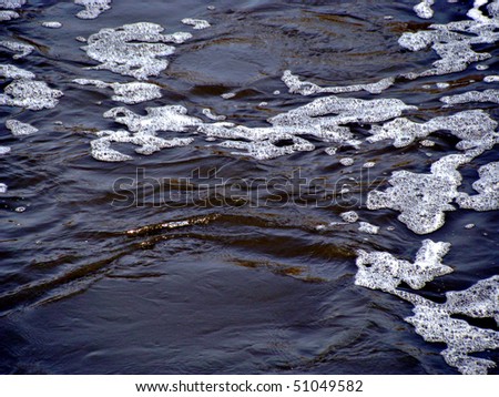 Dark river water with suds and waves