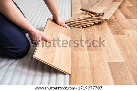 Installing laminated floor, detail on man hands holding wooden tile, over white foam base layer, small pile with more tiles background Foto d'archivio © 