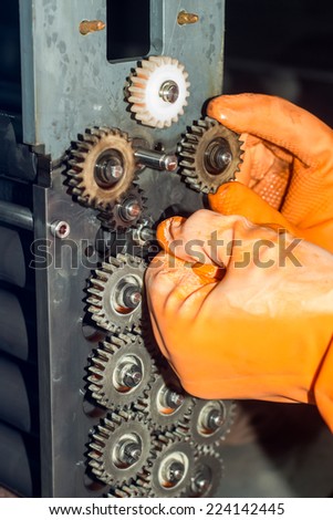 Gloved hands repairing gears of photo printer