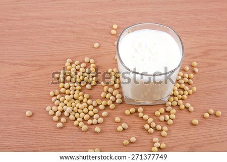 Soy milk in glass with soybeans on wooden background.