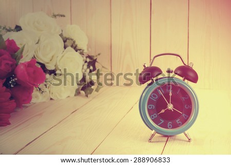 Vintage wood background and flowers with retro alarm clock