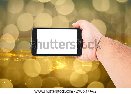 Man hand hold touch screen smart phone on abstract blurred bokeh of city night light background.