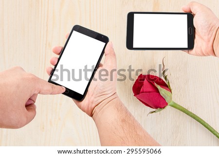 Man hand hold blank touch screen smart phone on background with red roses on wood texture for background.
