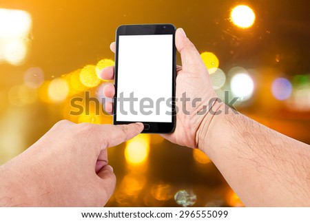 Man hand hold blank touch screen smart phone on abstract blurred bokeh of night light background.