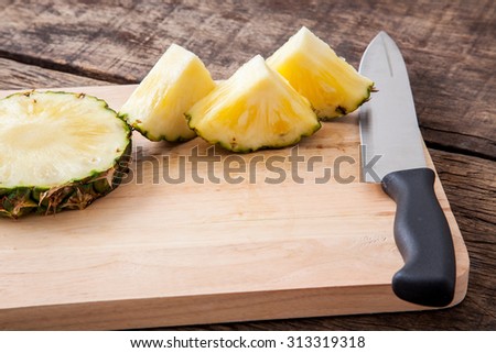 pineapple slice and knife on wooden cutting board, on wooden table top