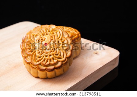 Moon cakes on wooden plate for the chinese Mid-Autumn festival on black background