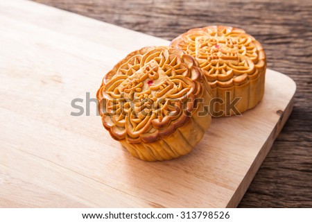 Moon cakes on wooden plate for the chinese Mid-Autumn festival, on wooden table top