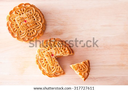 Two Mooncake with one cut up for the chinese Mid-Autumn festival on wooden board