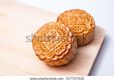 Mooncake for Mid-Autumn festival on wooden cutting board, on white table