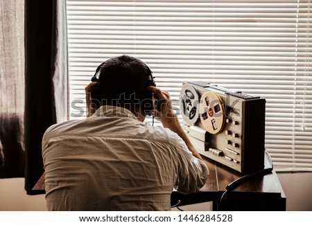 Special agent listens on the reel tape recorder. Officer wiretapping in headphones. KGB spying of conversations. Foto stock © 