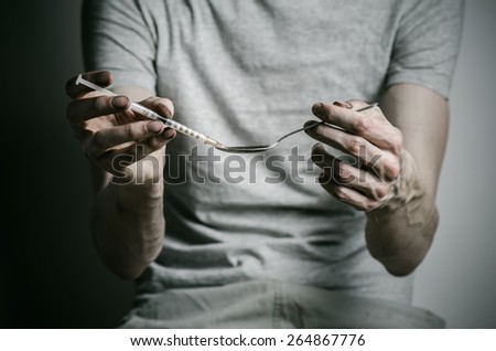 The fight against drugs and drug addiction topic: addict gaining a dirty syringe liquid drug from a spoon on a dark background