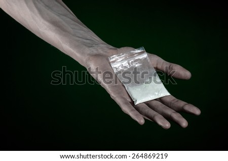 The fight against drugs and drug addiction topic: dirty hand holding a bag addict cocaine on a dark green background in the studio