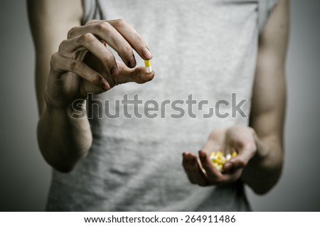 The fight against drugs and drug addiction topic: addict holding a narcotic pills on a dark background