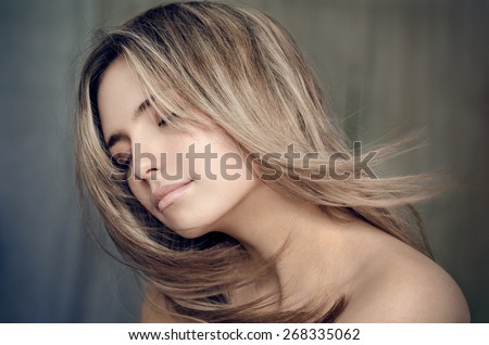 Dramatic portrait of a girl theme: portrait of a beautiful lonely girl with flying hair in the wind isolated on dark background in studio