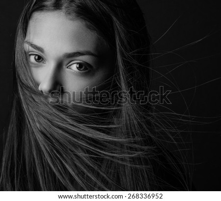 Dramatic portrait of a girl theme: portrait of a beautiful girl with flying hair in the wind against a background in the studio