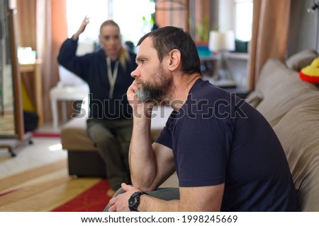Photo man unhappy listens to the girl in the background on the couch at home Сток-фото © 