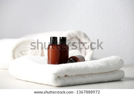 Mini bottles with cosmetic products and towels on table against light background. Hotel amenities Stock foto © 