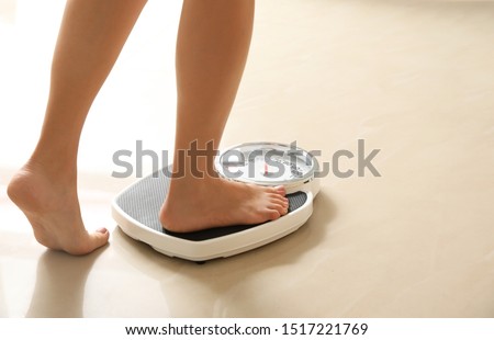 Woman stepping on floor scales indoors, space for text. Overweight problem Photo stock © 