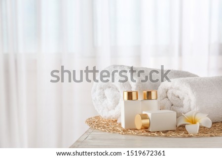 Cosmetic bottles, flower and towels on white wooden table indoors, space for text. Spa treatment Stock foto © 